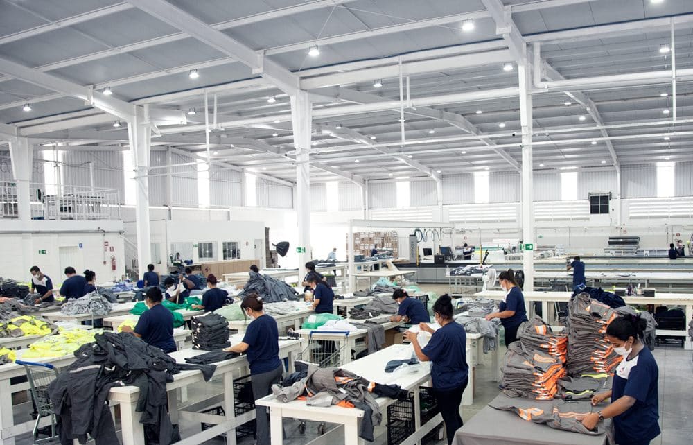 Fardas production floor with teams finishing and folding industrial uniforms across long working tables.