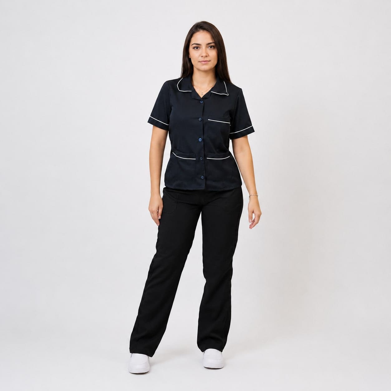 Facilities professional wearing a navy cleaning service tunic with white piping and black trousers.